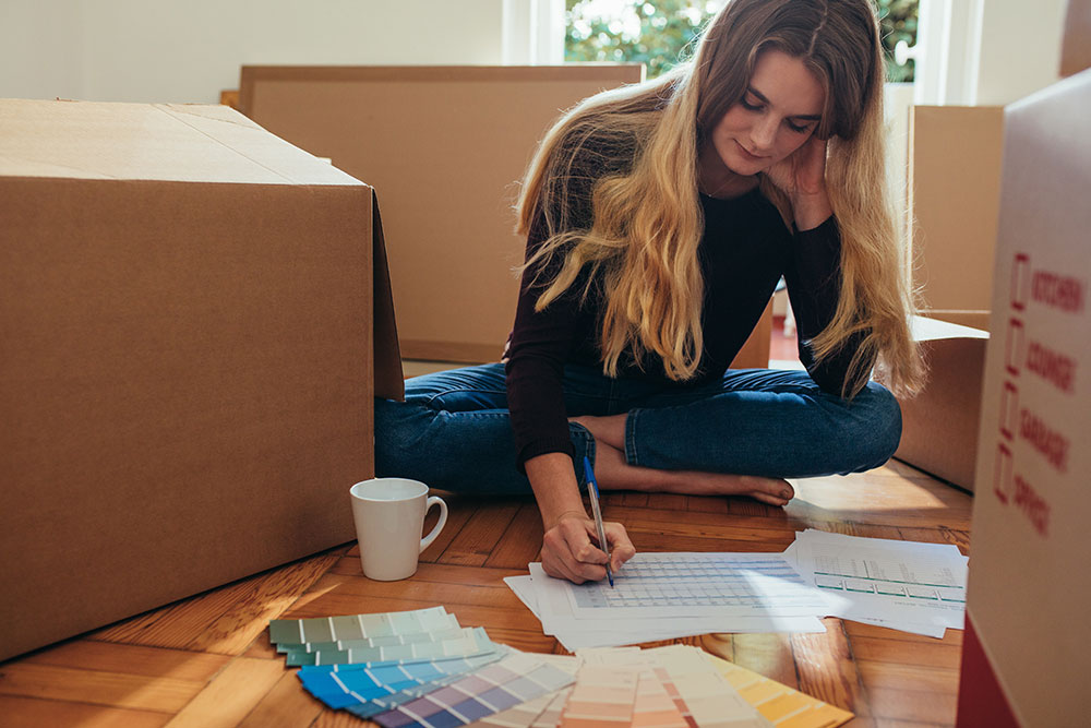 Young woman using a moving checklist to organize her to-do’s such as scheduling a home inspection and changing her address.